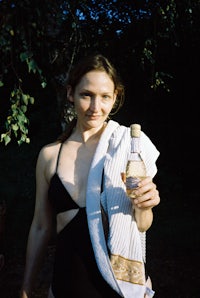 a woman in a black bathing suit holding a bottle of wine