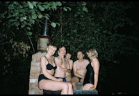 a group of people in bathing suits sitting on a brick wall