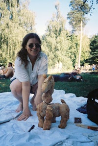 a woman kneeling on a blanket in a park