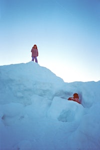 two people standing on top of a snow covered hill