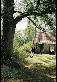 a girl is swinging on a swing in front of a house