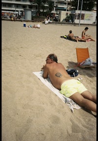 a man laying on a towel in the sand