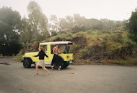 a woman is walking next to a yellow jeep