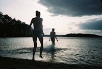 two people standing on the shore of a body of water