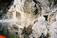 a man is standing on a rocky cliff next to a waterfall