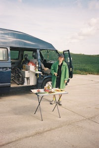a person standing in front of a van with food on a table