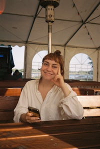 a woman is sitting on a wooden bench in a tent