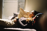 a woman laying on a couch in front of a window