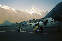 a plane parked on a tarmac with mountains in the background