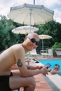 a man sitting on a bench next to a swimming pool