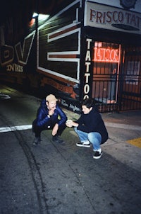 two men squatting on a street at night