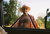 a man in a hat is standing in the doorway of a car