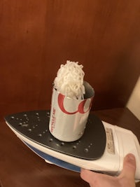 a person holding a can of coca cola on an iron
