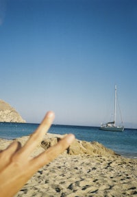 a person is making a peace sign on a beach