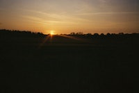 the sun is setting over a field