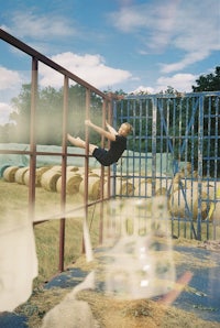 a boy jumping over a fence in a field