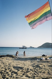 a rainbow flag is flying over a beach