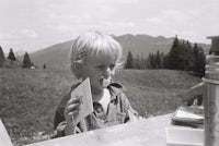 a young boy eating a piece of paper at a picnic table