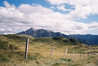 a dirt road with a fence and mountains in the background